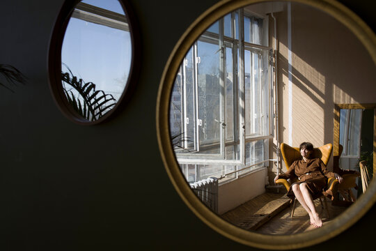 Reflection of mother sitting on  armchair