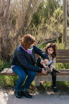 Woman helping girl to put on shoe in park