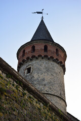 Fototapeta na wymiar High round watchtower of a medieval fortress or castle on a blue sky background