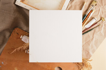 white cotton canvas on cardboard and various artist tools mock up background, blank square canvas,...