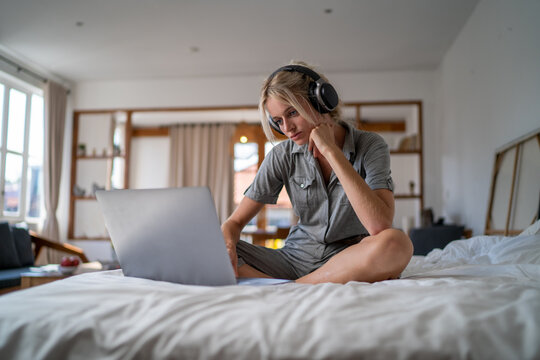 Woman sitting on bed with her laptop in front of her