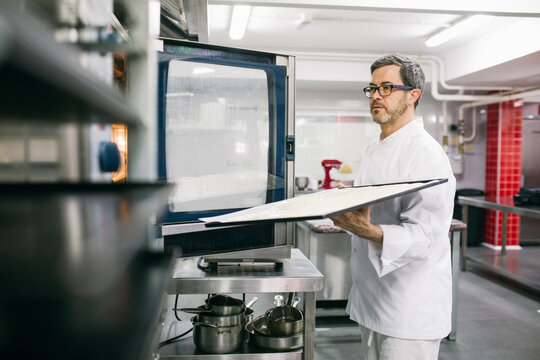Man placing cooking tray in oven 