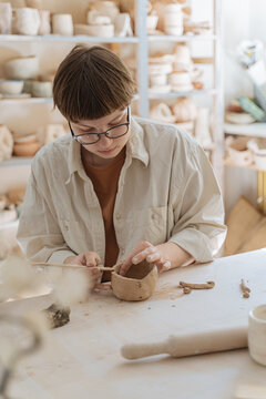 Young woman creating clay cup in pottery