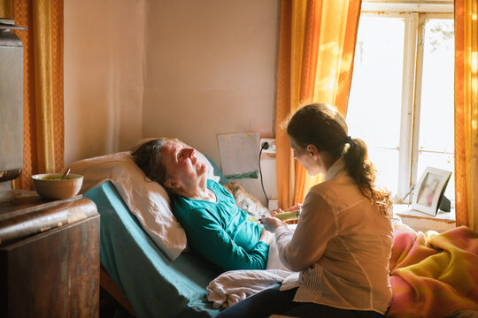 Feeding Senior Woman With Disability In The Bed

