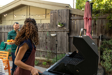 Woman at a Grill Looking at Man Bringing Over Food
