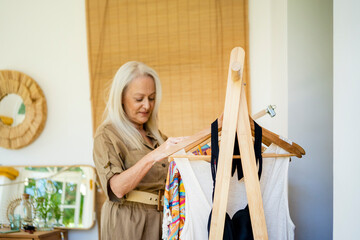 Senior woman choosing outfit at home