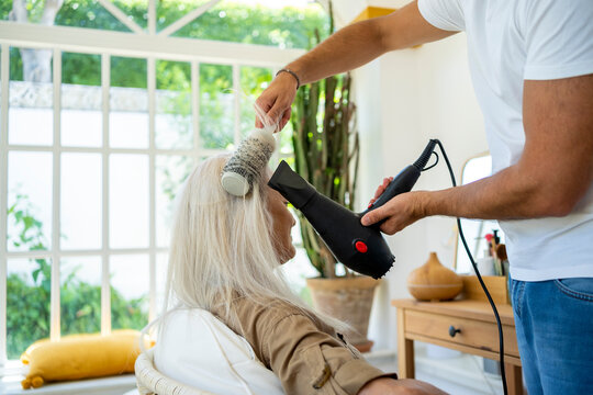 Hairdresser combing a woman's hair at home