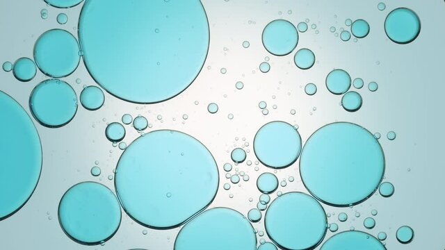 Big blue transparent bubbles move slowly from the center in clear liquid being replaced by small ones on tile background | Background for moisturizer commercial