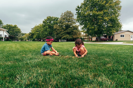 Kids playing in front yard using their imaginations. 
