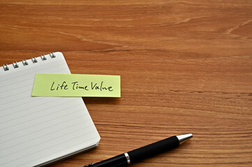 There is sticky note with the word of Life Time Value on the desk board with a pen.