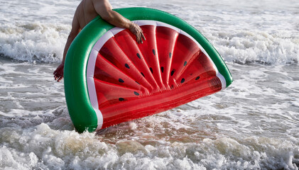 Close up a watermelon shaped swimming toy by the sea

