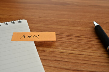 There is sticky note with the word of ABM which is an abbreviation for Account Based Marketing on the desk with a pen.