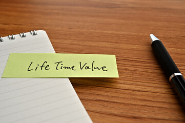 There is sticky note with the word of Life Time Value on the desk board with a pen.