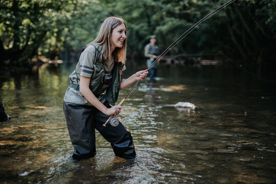 Young adult couple with dog is fishing together on fast mountain river. Active people and sport fly fishing concept.