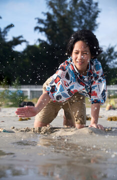 Cute beautiful Asian girl playing sand sculpture on the beach by the sea