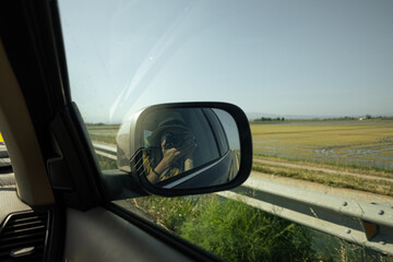 Reflection of a woman in the rear view mirror of the car