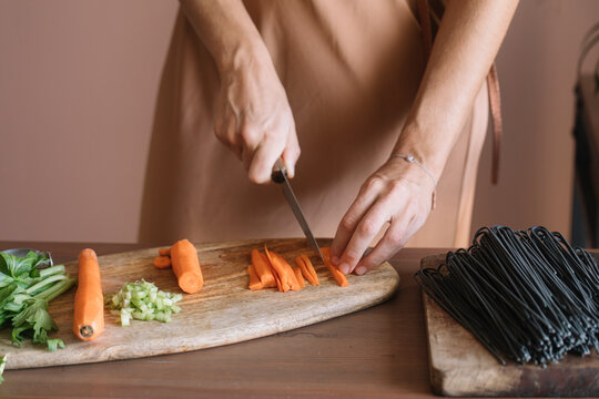 Anonymous Woman Cutting Vegetables Squid Ink Spaghetti