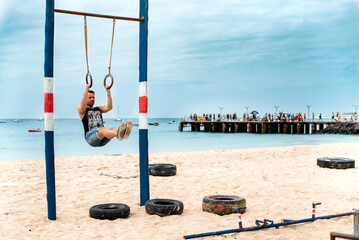 Fototapeta premium Man in a gymnastic rings in a beach