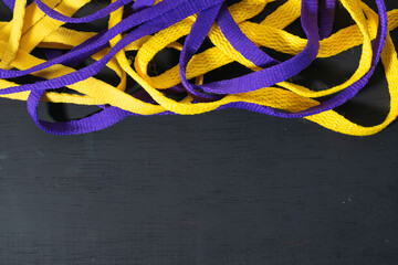Yellow and purple shoelaces, Lakers flag, neatly placed on black wooden background, leaving space...