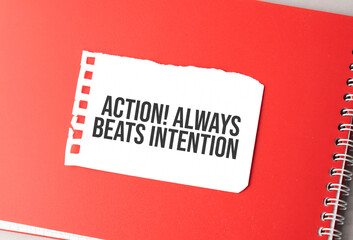 The word Action Always beats intention on torn paper on red notepad,.