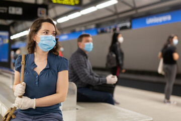 Personal protection during a pandemic. Woman in protective medical mask and gloves is standing on platform and waiting train