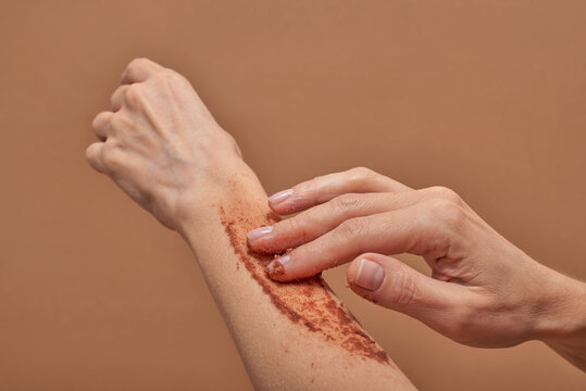 Unrecognizable female applying scrub on arm