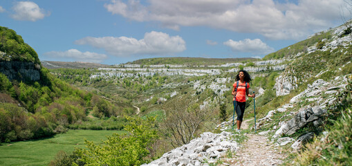 woman hiking with trekking poles in mountains