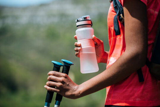 Black woman with water bottle and trekking poles