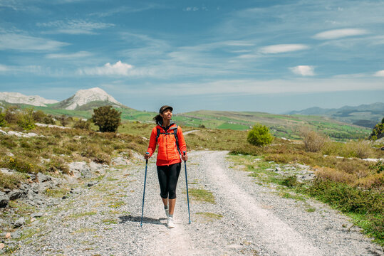 woman hiking with trekking poles in mountains