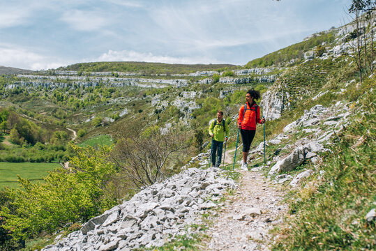 Multiracial hikers with backpacks and trekking poles exploring rocky terrain