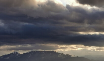 Nuvole tempestose sopra le montagne  e raggi di sole al tramonto