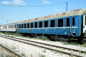 Obraz premium old and rusty abandoned passenger wagons, carriage car, lost and let to rot in a closed train station yard, rusting, after a collapse in traffic and an economic crisis
