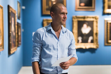 Portrait of European adult man standing in gallery and watching exposition