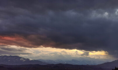 Fototapeta na wymiar Nuvole rosse sopra le cime innevate dei monti Appennini