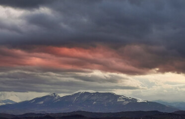 Fototapeta na wymiar Nuvole rosse sopra le cime innevate dei monti Appennini