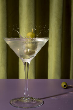 Olives splashing into a martini cocktail