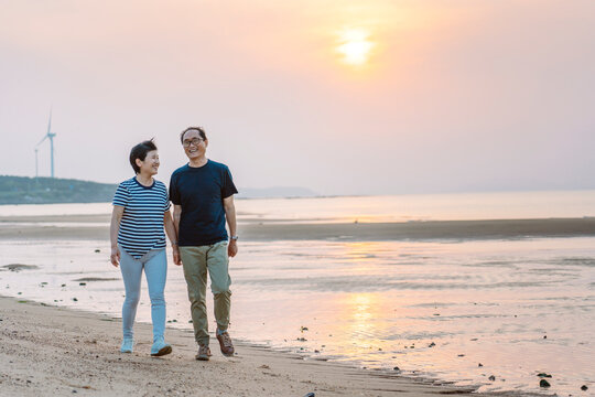 mature couple walking on beach at sunset