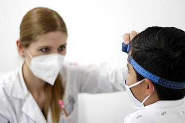 Female professional pediatrician doctor working checking a happy latin child
