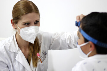 Female professional pediatrician doctor working checking a happy latin child
