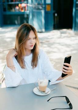 Young woman taking a selfie sitting on a cafe terrace