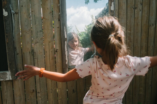 Child looks at her reflection in an outdoor mirror 