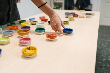 Crop woman displaying colorful handmade bowls