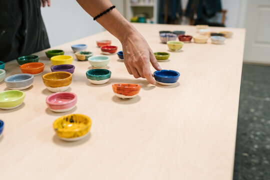 Crop woman displaying colorful handmade bowls