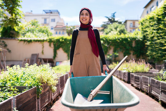 Muslim woman with wheelbarrow in urban garden