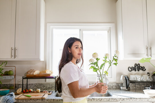 Young woman with bouquet of flowers in home kitchen