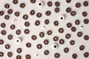A lot of black rings cerial and candy monsters eyes in white milk, breakfast background. Concept...