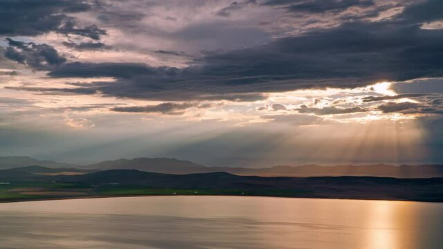 Time lapse of sun rays beaming through the clouds over Utah Lake during timelapse.