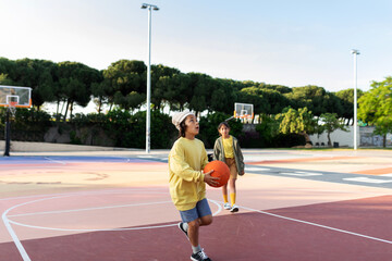 Kid playing basketball after school at sports area