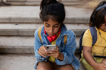 Little girl using her phone at school park