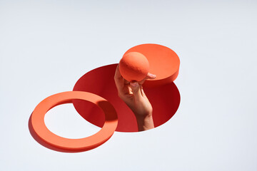 Cropped shot of female hand holding ball through holes on bright background